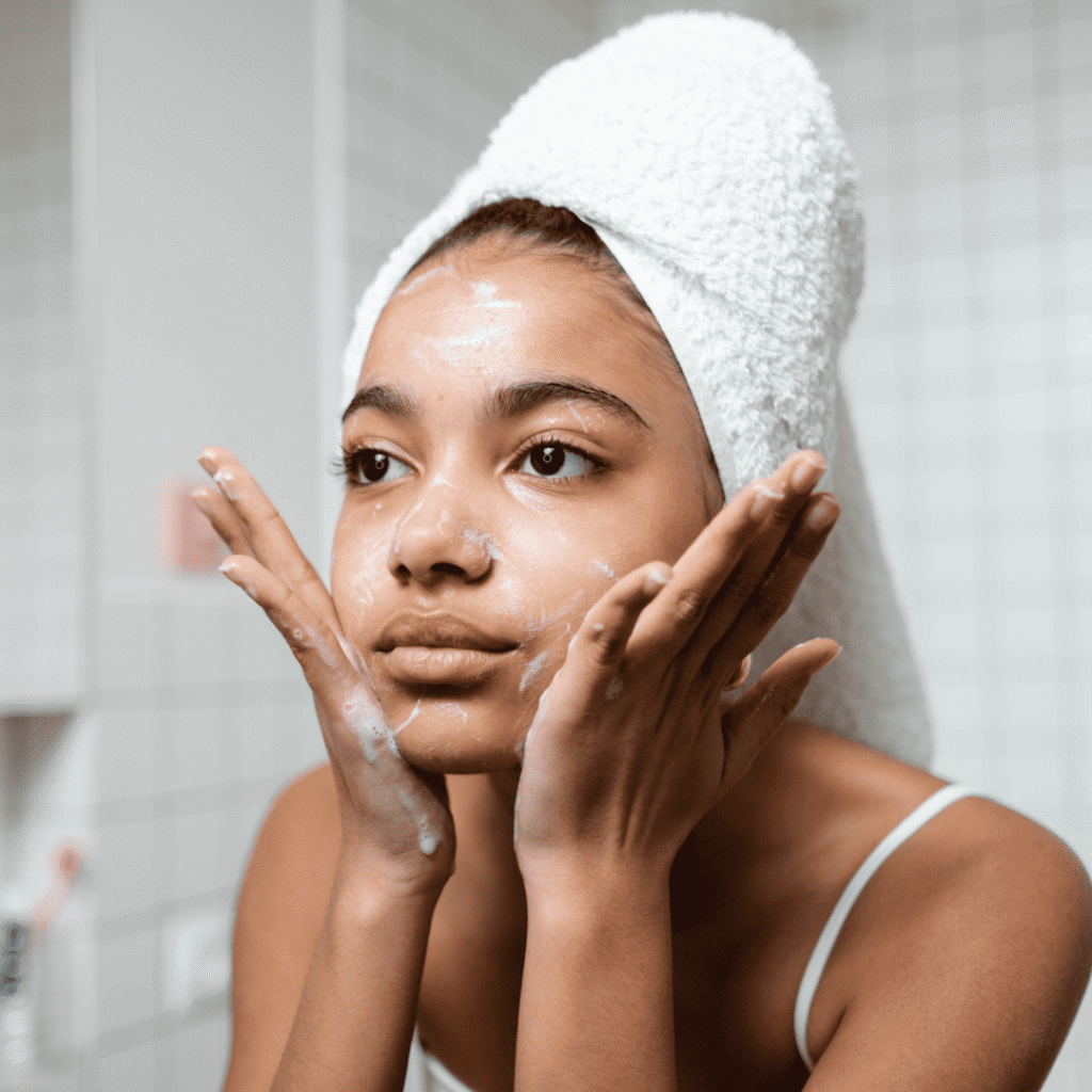 Skinimalismo e Rotinas Simplificadas. Na imagem, vemos uma mulher na sua rotina de skincare lavando o rosto, representando o primeiro passo essencial do Skinimalismo: a limpeza suave da pele. 